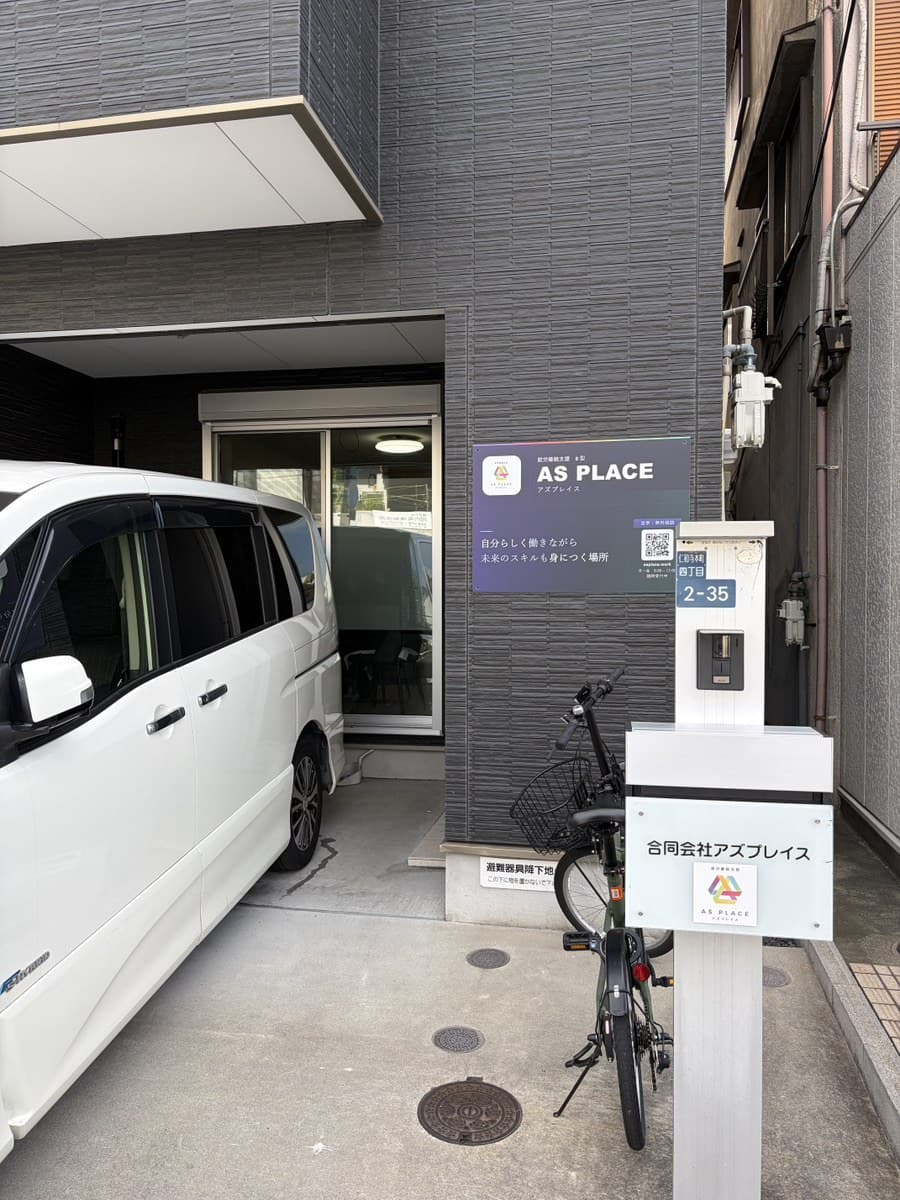 アズプレイスの建物の外観。入口の横に看板が出ている